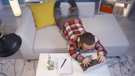 Midget-man-working-on-computer-lying-down-at-home.